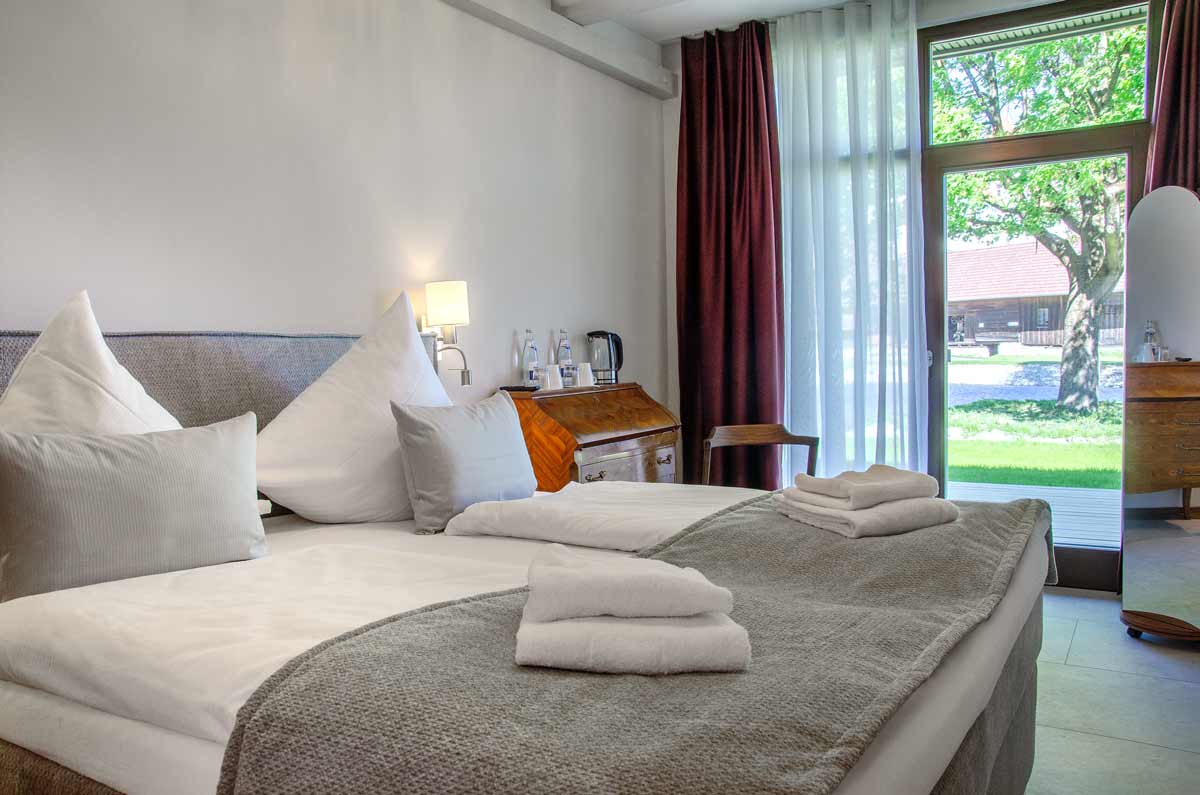 Das Bett im Classic Zimmer des Hotels Remisenhof mit Blick in den Garten.