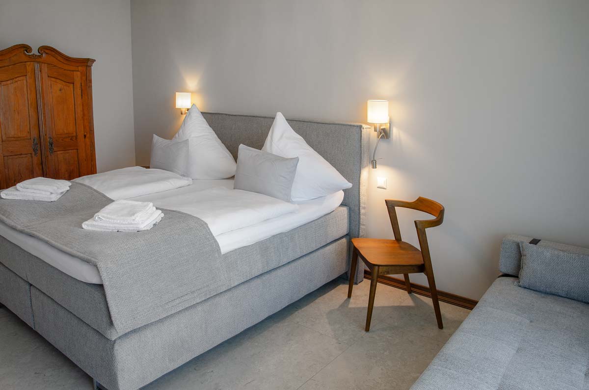 Das Bett im Comfort Zimmer mit Stuhl im Vordergrund.