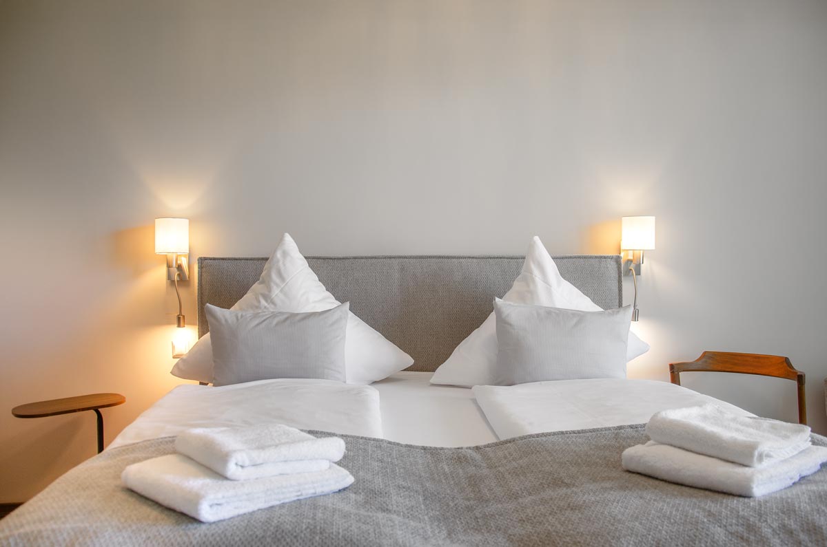 Das frisch gemachte Bett im Comfort Zimmer mit unbenutzten Handtüchern.